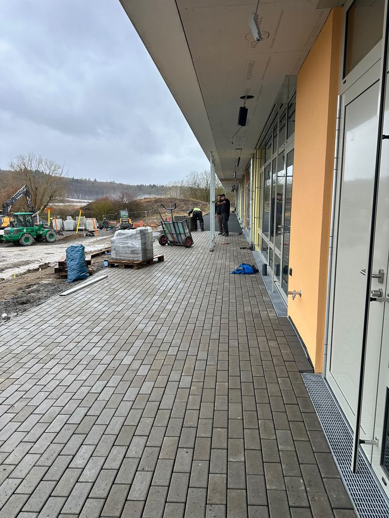 Frisch verlegtes Pflaster mit Entwässerungsrinne vor einem Gebäude